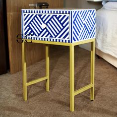 a blue and white table sitting on top of a carpeted floor next to a bed