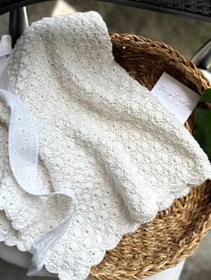 a white blanket sitting on top of a wicker basket next to a green plant