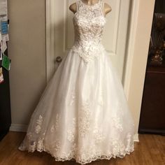 a white wedding dress is on display in front of a door with a wooden floor