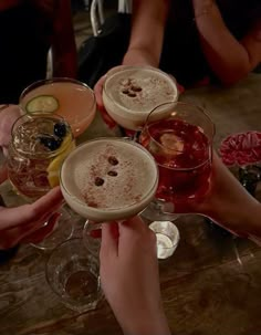 several people holding up wine glasses with drinks in them