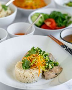 a white plate topped with rice and veggies next to bowls filled with vegetables