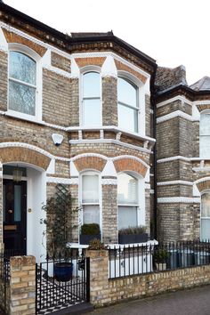 a row of brick houses with white windows and black wrought iron fence on the sidewalk