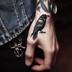 a person with a black bird tattoo on their arm and wrist, holding onto the other hand