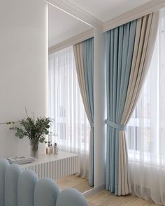 a living room with blue chairs and curtains on the windowsills, along with a plant in a vase