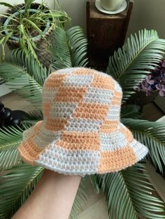 a crocheted hat sitting on top of a palm tree next to a potted plant