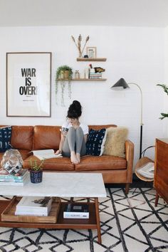 a woman sitting on top of a brown couch in a living room next to a coffee table