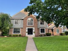 a brick house with grass and trees in the front yard