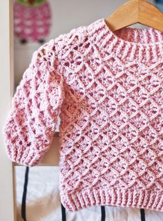 a pink knitted sweater hanging on a wooden hanger