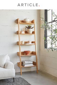 a living room with a white couch and wooden shelves on the wall next to a window