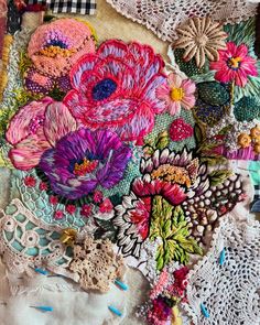 an assortment of colorful flowers and laces on a piece of cloth with crochet