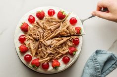 someone is cutting into a cake with chocolate frosting and strawberries on the side