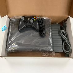 an open box with a game controller and charger in the middle, sitting on top of a table