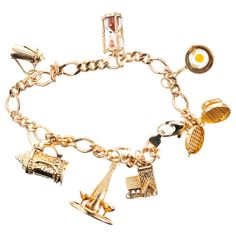 Figaro style 14k yellow gold charm bracelet. Food and drink motif charm bracelet consists of seven charms. A waffle iron, frying pan with egg, sand timer, carafe stein, champagne bottle and glasses and a tavern all in 14k yellow gold. 7.75 inches long. 14k yellow gold Stamped: 14k 24.7 grams Bracelet: 7.75 Inches Cheap Gold Charm Bracelets, Luxury Vintage Charm Bracelet, Luxury Gold Round Charm Bracelet, Luxury Yellow Gold Fine Jewelry Charm Bracelet, Cheap Yellow Charm Bracelet For Gift, Gold Charm Bracelet Gift, Sand Timer, Sand Timers, Jewelry Words