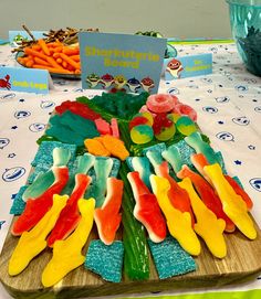 a wooden tray topped with gummy bears and carrots on top of a table