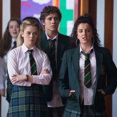 three girls in school uniforms standing next to each other with their arms crossed and looking at the camera