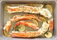 cooked crab legs with lemons and herbs in a baking pan, ready to be eaten