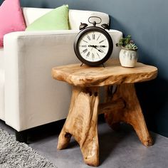 a wooden table with an alarm clock on it next to a white couch and potted plant