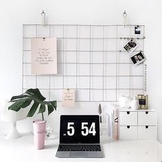 a laptop computer sitting on top of a white desk next to a potted plant