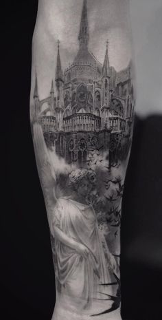 a man's leg with a black and white tattoo design on it, featuring a statue in front of a castle