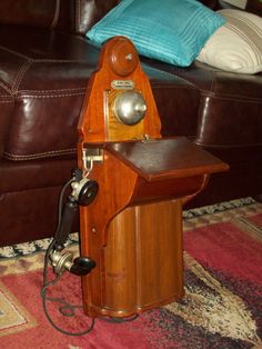 an old fashioned telephone sitting on top of a wooden table next to a brown couch