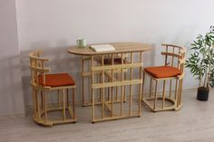 three chairs and a table with an open book on it in front of a plant