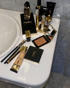 various makeup products are sitting on a white counter top next to a sink in a bathroom