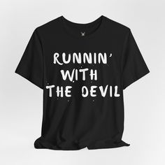 The "Runnin' with the Devil" unisex t shirt is a nod to rock 'n' roll rebellion. Perfect for music lovers and those who embrace their wild side, this tee captures the essence of classic rock with its edgy design. The bold text pops against the fabric, making a statement that's both daring and timeless. Whether you're hitting a concert, hanging out with friends, or simply want to showcase your rock-inspired style, this t shirt is the perfect choice for adding a rebellious edge to your wardrobe. SHABBY RABBIT T SHIRTS Discover unique, high-quality apparel at The Shabby Rabbit, your go-to destination for stylish and quirky t-shirts. We specialize in creating fun and original designs that cater to every personality, from vintage-inspired graphics to modern, edgy prints. Whether you're looking Slogan T-shirt For Alternative Fashion, Grunge Short Sleeve T-shirt For Concert, Punk Style Pre-shrunk Short Sleeve Shirt, Halloween Concert T-shirt With Screen Print, Black Punk T-shirt With Slogan, Edgy Short Sleeve T-shirt With Band Logo, Rock Style Crew Neck T-shirt For Streetwear, Halloween Concert T-shirt With Crew Neck, Edgy Halloween T-shirt With Screen Print