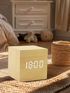 an alarm clock sitting on top of a wooden block next to a basket and stuffed animal