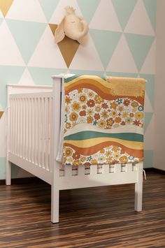 a baby crib with a blanket on it in front of a wall decorated with triangles