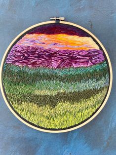 an embroidery project with grass and mountains in the background