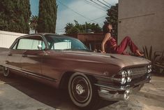 a woman sitting on the hood of an old car