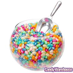 a bowl filled with lots of candy and a metal spoon in it's center