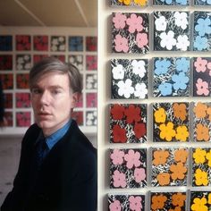 a man standing in front of a wall covered with colorful paper flowers on it's side