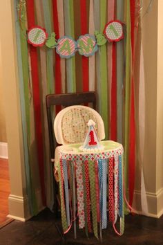 a baby's high chair sitting in front of a wall with decorations on it