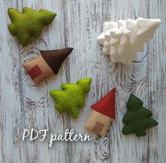 four felt christmas trees sitting on top of a white wooden table next to each other