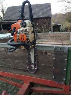 an orange and black chainsaw sitting on the back of a truck