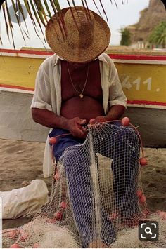 a man sitting on top of a boat next to a net covered in sand and seaweed