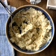 a bowl filled with mashed potatoes on top of a wooden table