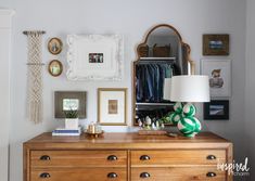 a dresser and mirror in a room with pictures on the wall above it, along with other items