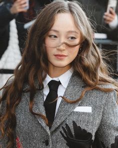 a woman with long hair wearing a gray jacket and black tie is posing for the camera