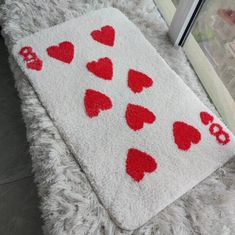 a rug with red hearts on it next to a window