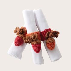 three napkins with crocheted animals on them are hanging from white napkin holders