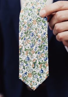 a man wearing a suit and tie is holding his hand in front of the camera