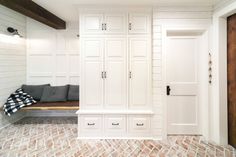 a room with white cabinets and a bench on the floor in front of some pillows