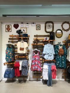 a clothing store display with clothes on wooden racks and hanging items in front of them