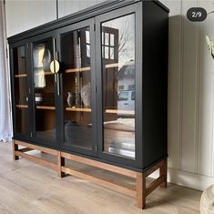 a large black cabinet sitting next to a vase on top of a hard wood floor