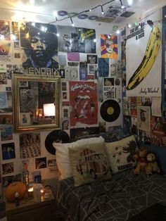 a bed room with a neatly made bed and lots of posters on the wall above it