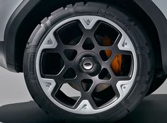 the front wheel of a grey car with orange brake pads