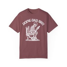 ✨💀 Introducing our "Doing Dad Shit" Skeleton T-Shirt! 💀✨ 🎉 Celebrate Father's Day with a humorous twist by gifting this custom tee featuring a skeleton on a toilet and the phrase, "Doing Dad Shit"! 🎉 💖 Crafted from 100% ring-spun cotton, this garment-dyed t-shirt offers unbeatable softness and comfort, perfect for everyday wear. 💖 😌 The soft-washed fabric adds an extra layer of coziness, making this tee an ideal choice for dads who appreciate both comfort and humor. 😌 💪 With double-needle stitching throughout, this tee is built to last, ensuring durability for all of dad's adventures. 💪 🔄 Say goodbye to bothersome side-seams – our shirt maintains its tubular shape for a sleek and flattering fit. 🔄 🎨 Show your appreciation with this fully customizable design featuring a playful Novelty Cotton T-shirt With Screen Print, Novelty Screen Print T-shirt For Streetwear, Novelty Screen Print Streetwear T-shirt, Novelty Streetwear T-shirt With Screen Print, Father's Day Band Merch T-shirt With Short Sleeves, Father's Day Band Merch T-shirt, Funny Screen Print T-shirt For Father's Day, Funny Relaxed Fit Pre-shrunk T-shirt, Father's Day T-shirt With Funny Print In Relaxed Fit