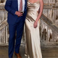 a man and woman standing next to each other in front of an old wooden wall